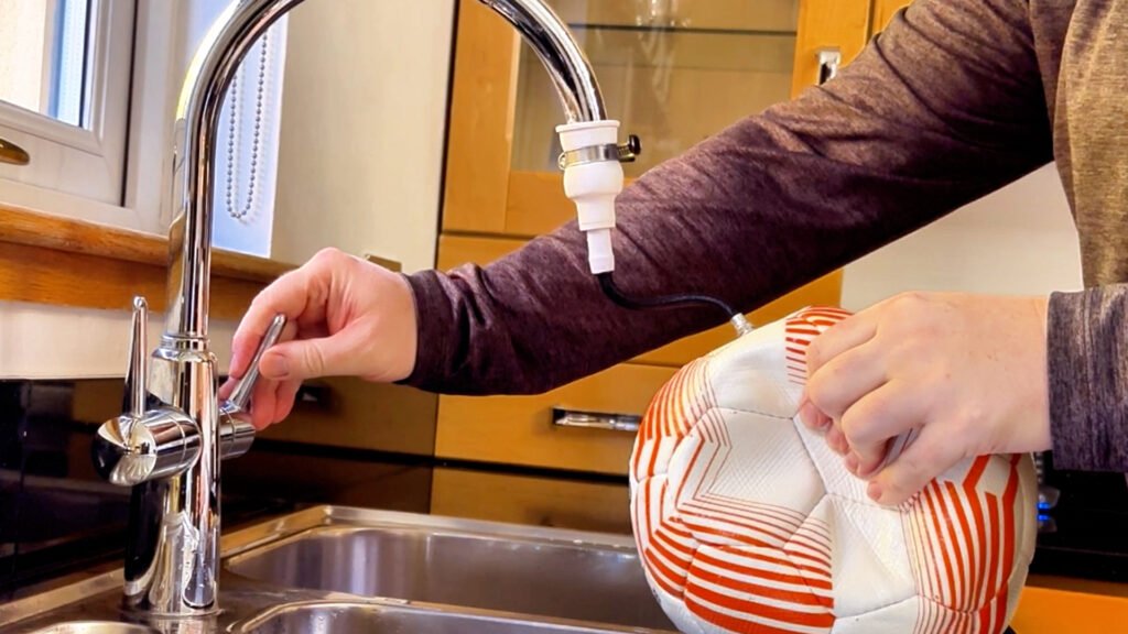 Filling a soccer ball with water using the Long Throw Coach universal tap adapter to create a weighted training ball.