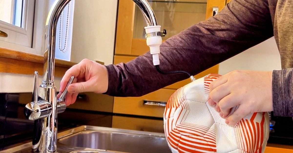 Filling a soccer ball with water using the Long Throw Coach universal tap adapter to create a weighted training ball.
