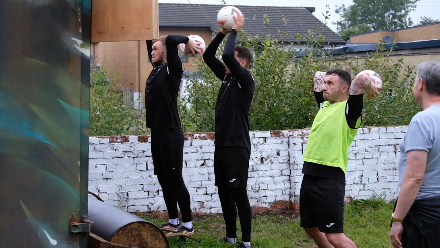 Players doing heavy ball throw-in training against a wall at a Long Throw Coach session